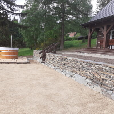 Kamenná zídka a dřevěné pódium pod saunu